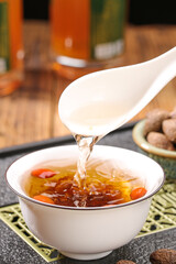 Traditional herbal soup being served with ladle, healthy nourishing broth with goji berries and natural ingredients