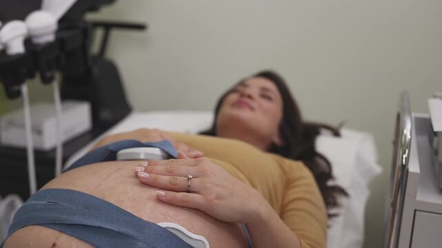 Beautiful young pregnant woman at electrocardiograph check up for baby health and expected date of birth. Fetal heart monitoring. Healthcare and medical service concept.