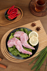 Raw Rabbit Legs with Asian Spices and Vegetables on Wooden Cutting Board for Traditional Cooking