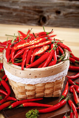 Fresh Red Chili Peppers in Wicker Basket on Rustic Wooden Background