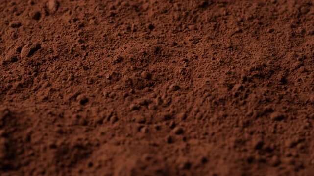 Natural dark brown cocoa powder textured background, close up, rotation. Heap of organic cacao powder