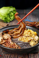 Asian Hot Pot with Squid and Mushrooms Lifted by Red Chopsticks