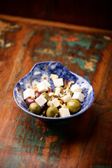 Green and kalamata olives and feta cheese on rustic wooden background. Soft focus.	