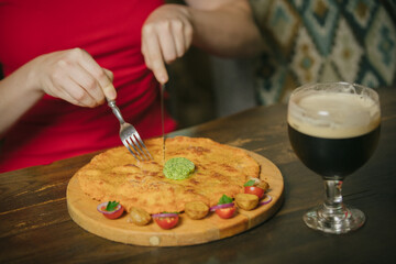 Person eating delicious khachapuri with dark beer in cafe