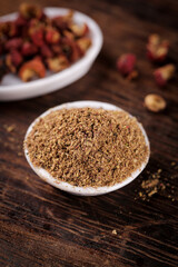 Ground Spice Powder in Bowl with Whole Spices on Rustic Wood Background