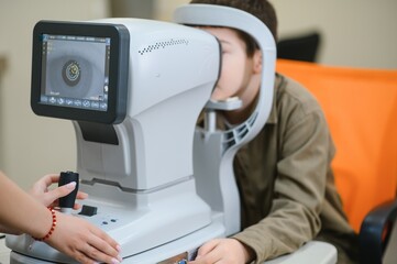 Ophthalmologist performing vision diagnostics on young patient using autorefractor