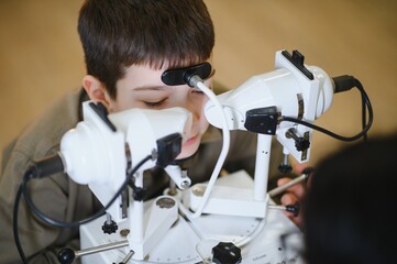 Boy undergoing vision diagnostics with modern equipment in ophthalmology clinic