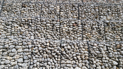 A roadside wall made of large white gravel and wire mesh for erosion control