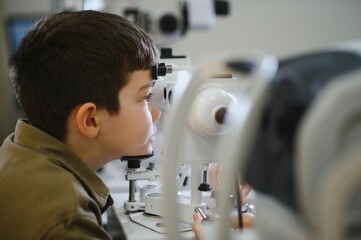 Boy undergoing eyesight examination with ophthalmic equipment in clinic