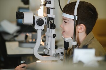 Boy undergoing vision diagnostics with slit lamp in ophthalmology clinic