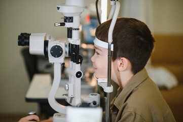 Young boy undergoing vision diagnostics with ophthalmologist in clinic