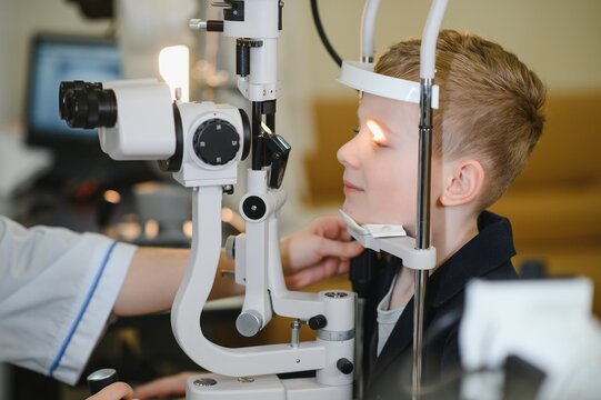 Ophthalmologist checking child's vision with modern equipment in clinic - Powered by Adobe