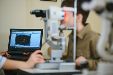 Ophthalmologist checking child's vision with modern equipment in clinic