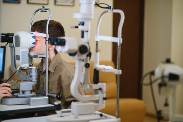 Boy undergoing vision diagnostics with ophthalmologist in clinic