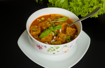 Close Up of Mediterranean Red Tomato Soup with Garlic, Basil, Spring Onion, Croutons, Lettuce on Black Background