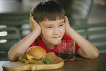 Young boy enjoying a burger and drink at cafe