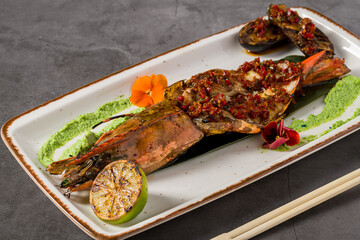 Grilled tiger shrimp served with green sauce, grilled lime, and herbs