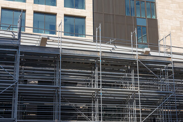 Metal scaffolding for repairing the facade of a modern building. Facade work at a height. Building construction. Cladding of the exterior walls of a new house.