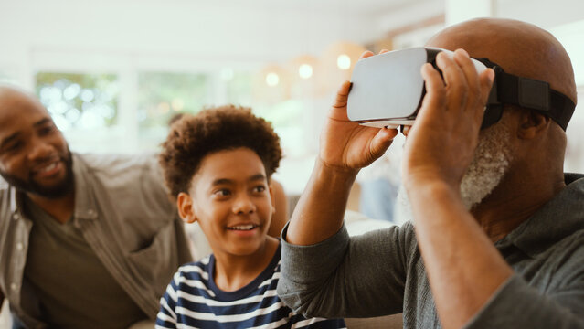 Grandfather Wearing VR Headset As Multi-Generation Male Family Sit On Sofa At Home Together
