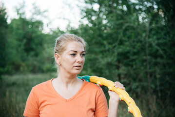 A woman is doing gymnastics in nature. A woman with a hoop in her hands. Outdoor sports. 