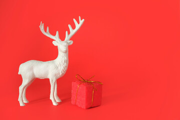 A festive composition featuring a delicate deer figurine surrounded by vibrant red gift boxes, set against a rich red background. 