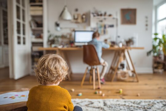 Toddler observing older sibling studying online at home