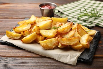 Tasty baked potatoes with rosemary on wooden table, closeup