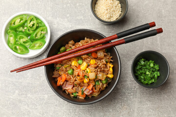 Delicious fried rice in bowl served on grey textured table, flat lay