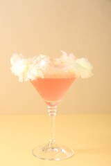 Tasty cocktail decorated with cotton candy on color background, closeup