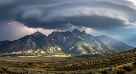 Dramatic Storm Clouds Looming Over a Sunlit Mountain Range.