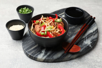 Tasty noodles with chicken and vegetables served on light grey table