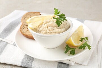 Tasty horseradish sauce with parsley and lemon slices served on light table, closeup