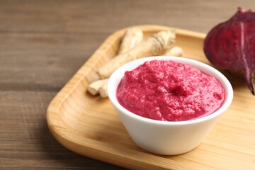 Tasty horseradish sauce with beetroot, roots and vegetable on wooden table, closeup