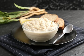 Tasty horseradish sauce served on black table, closeup