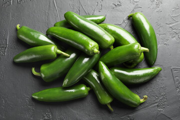 Fresh jalapeno peppers on black textured table, above view
