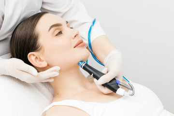 Woman receiving laser hair removal treatment in a cosmetology clinic, with a professional technician using advanced equipment for effective hair removal process