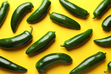 Green jalapeno peppers on yellow background, flat lay