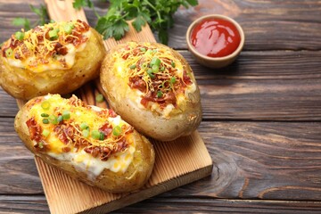 Tasty stuffed baked potatoes served on wooden table, closeup. Space for text
