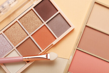 Colorful eyeshadow palettes and makeup applicator on color background, flat lay