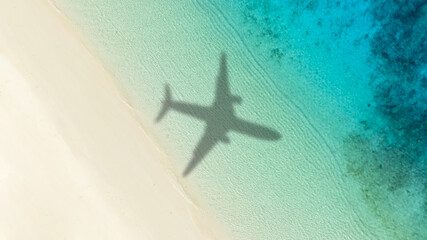 Aerial view of shadow passenger plane silhouette and sandy beach blue sea with waves at sea beach...