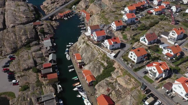 Aerial view of Sm&ouml;gen's vibrant harbor with boats docked along the pier, surrounded by red roofed buildings and rocky terrain, Sm&ouml;gen, V&auml;stra G&ouml;taland County, Sweden.