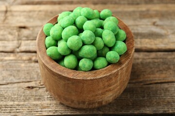 Delicious wasabi coated peanuts in bowl on wooden table, closeup