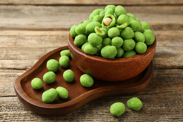 Delicious wasabi coated peanuts in bowl on wooden table, closeup