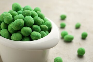 Wasabi coated peanuts in bowl on light table, closeup