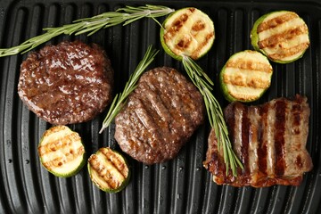 Electric grill with beef steaks, zucchini and rosemary, closeup