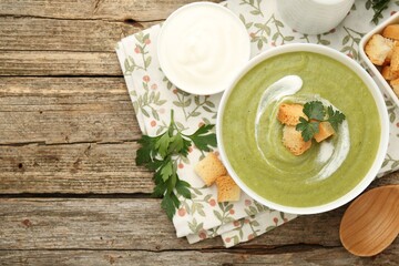 Tasty broccoli cream soup with croutons served on wooden table, flat lay. Space for text