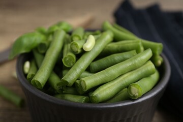 Pieces of fresh green beans in bowl on table, closeup