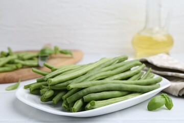 Fresh green bean pods on white tiled table, closeup