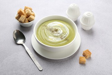 Tasty broccoli cream soup served with croutons on light grey table