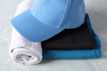 Stylish sportswear and towel on light grey table, closeup